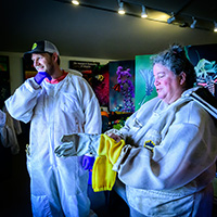 Nathan Beach, left, and Lesley Deem don full beekeeping suits with screened veils and protective gloves as they prepare their tools and materials for the hive transition. Photo by Fred Zwicky