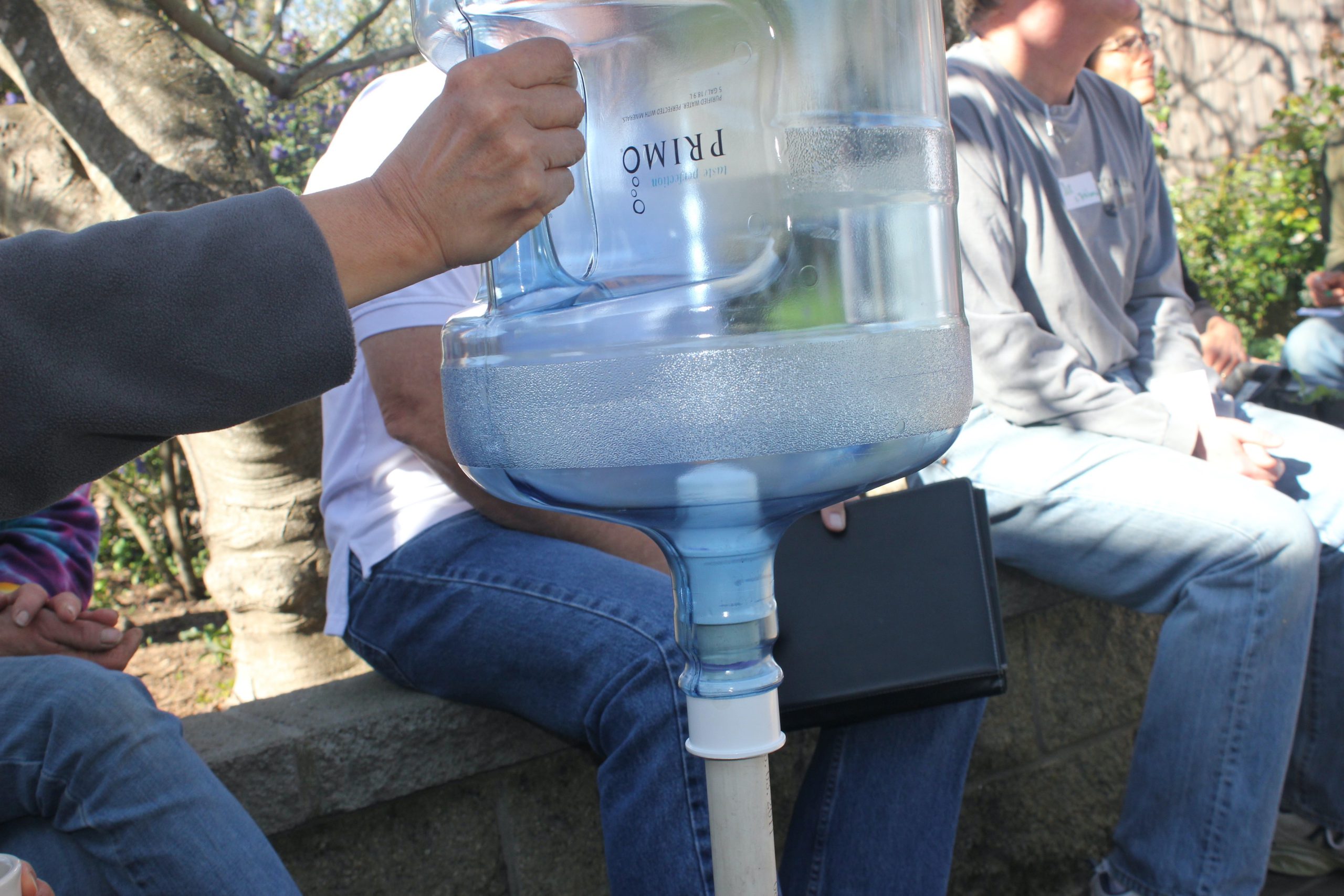 Close up of how a water jug can be turned into a swarm catcher. The pole slips in and out of the PVC adapter to make it easier for the beekeeper to dump the bees in the box. Advantage of this gadget is various lengths of poles can be used and the beekeeper can see from below the bees are in the jug.